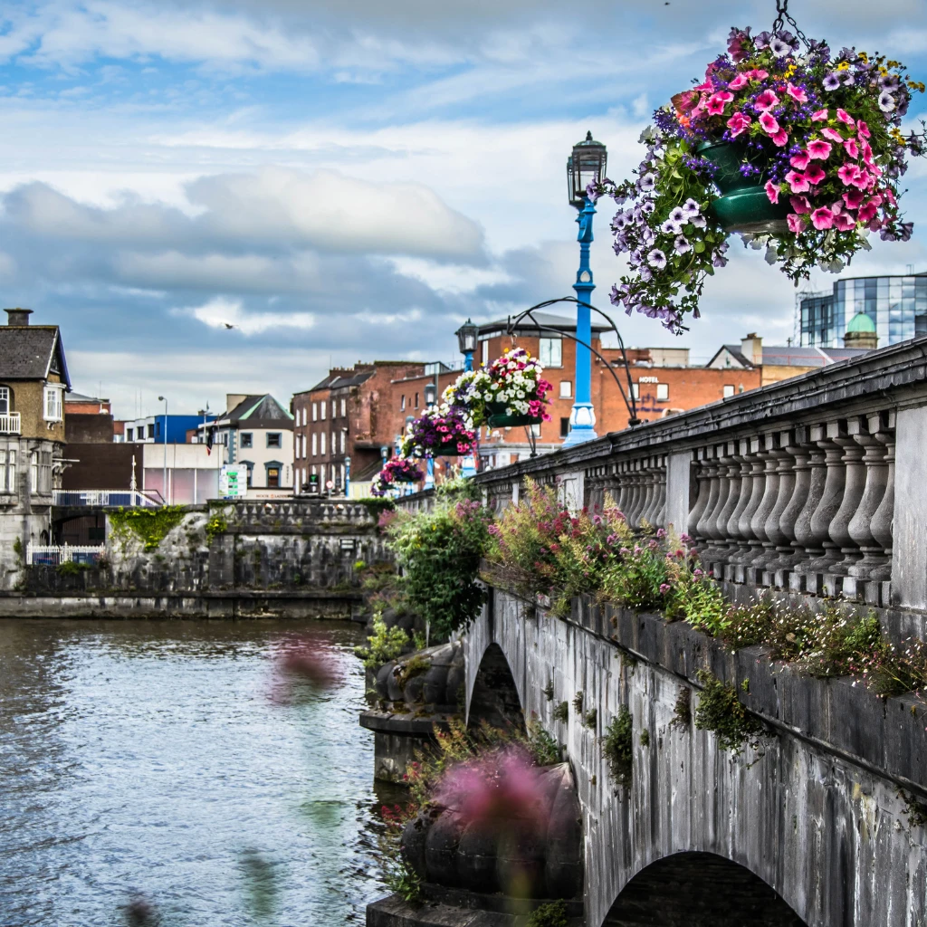 Flower-lined stone bridge over the River Shannon in Limerick, Ireland