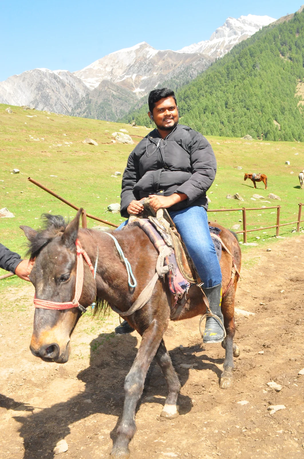 Jevon Max horse riding on an alpine meadow below snow-capped Himalayan peaks