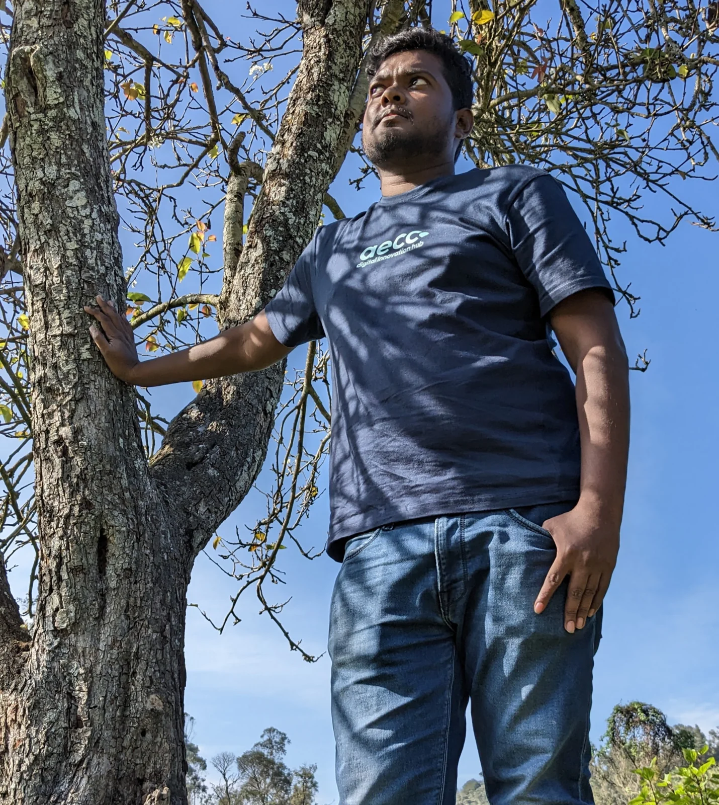 Jevon Max standing beside a tree on a hillside under a clear blue sky