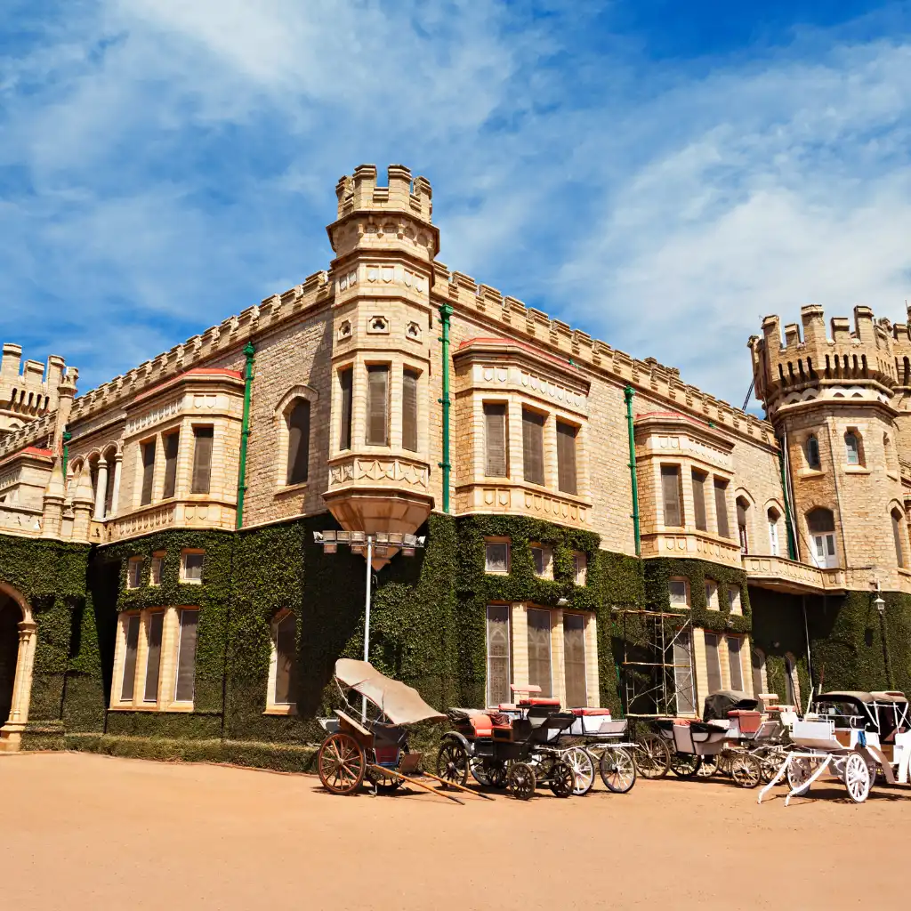 Bangalore Palace exterior with vintage carriages parked on the grounds