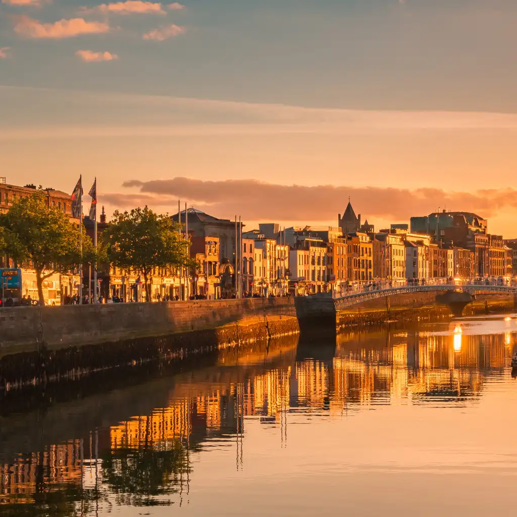 Dublin's River Liffey at sunset with glowing reflections of city buildings along the quay