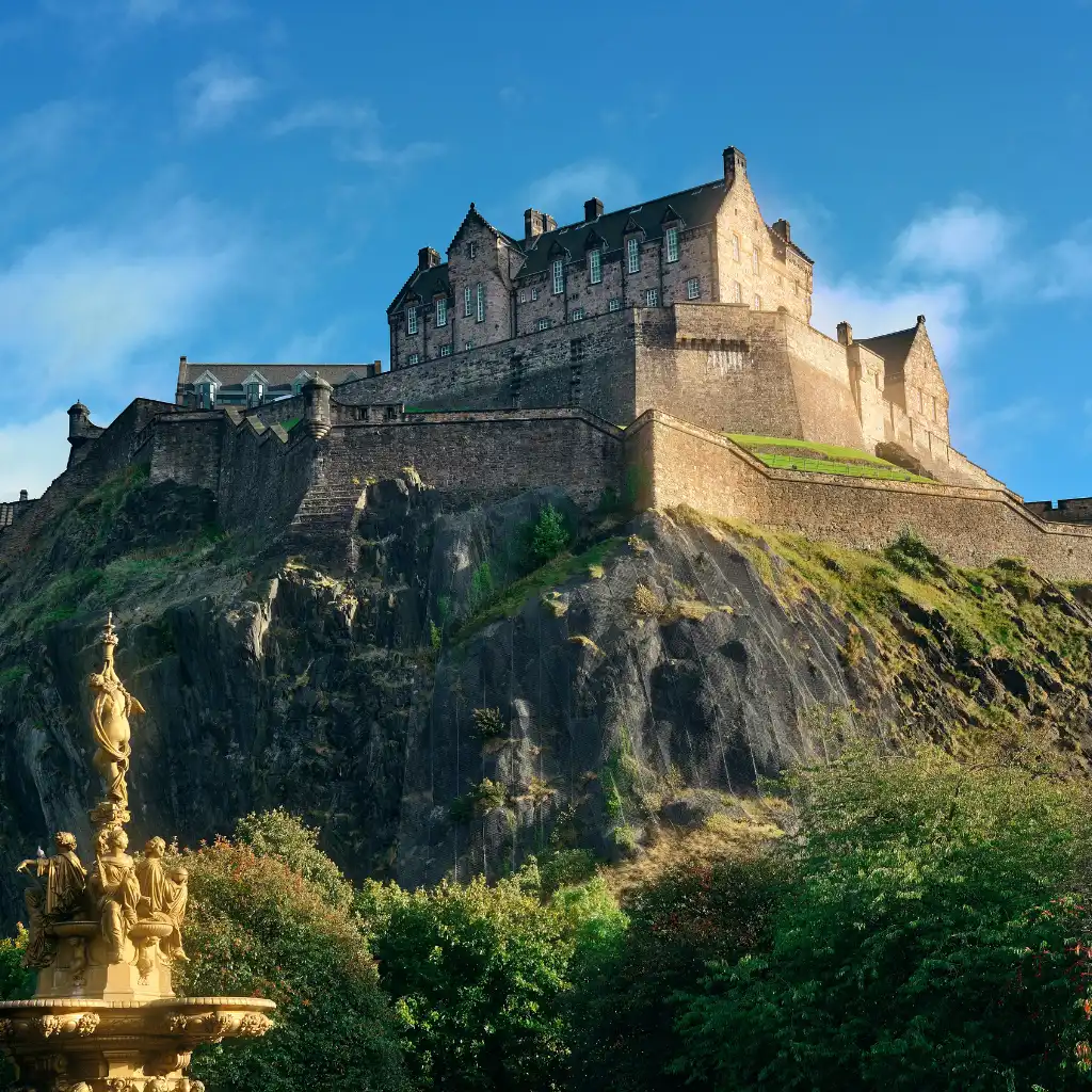 Edinburgh Castle on rocky cliffs with golden statue fountain, Scotland morning walk