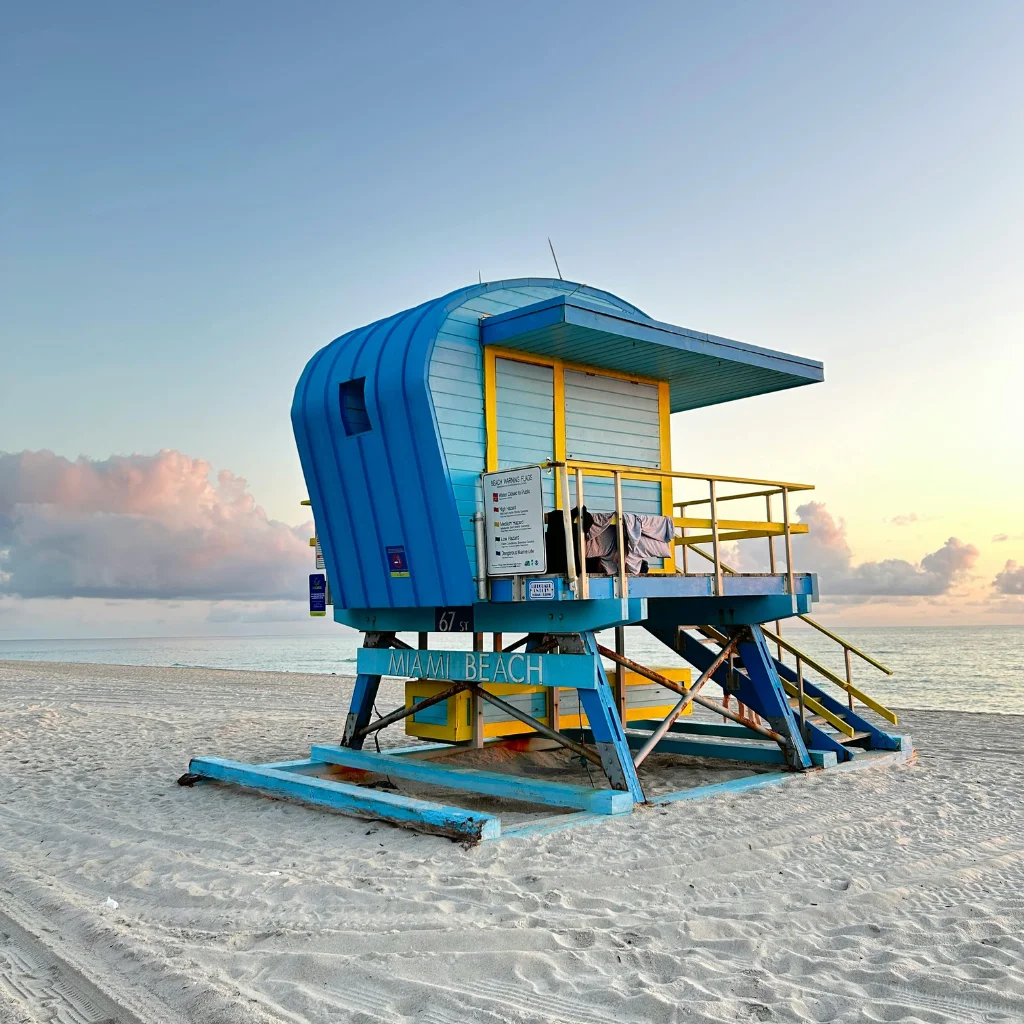 Miami Beach lifeguard tower on sandy shore with ocean and sunset sky in Florida