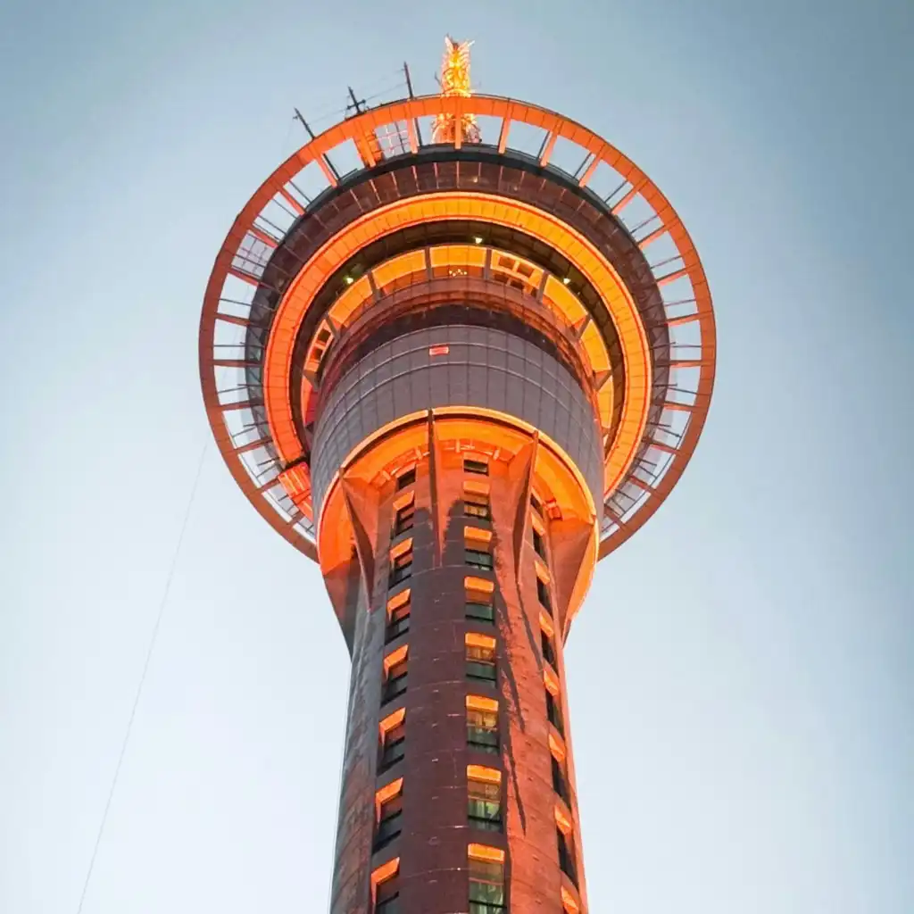 Sky Tower Deck Auckland glowing with orange lights at dusk viewed from below