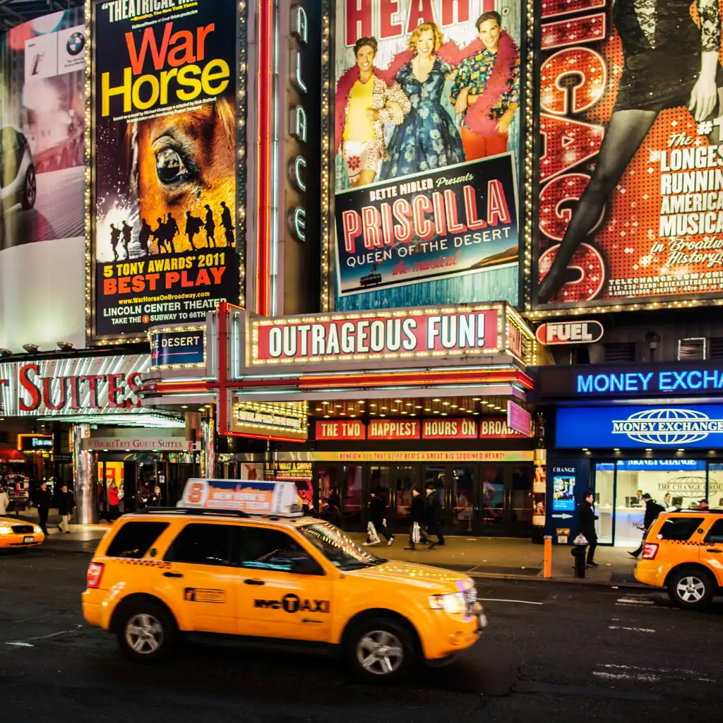 Yellow taxis on Broadway, New York outside theaters with War Horse and Priscilla marquees at night