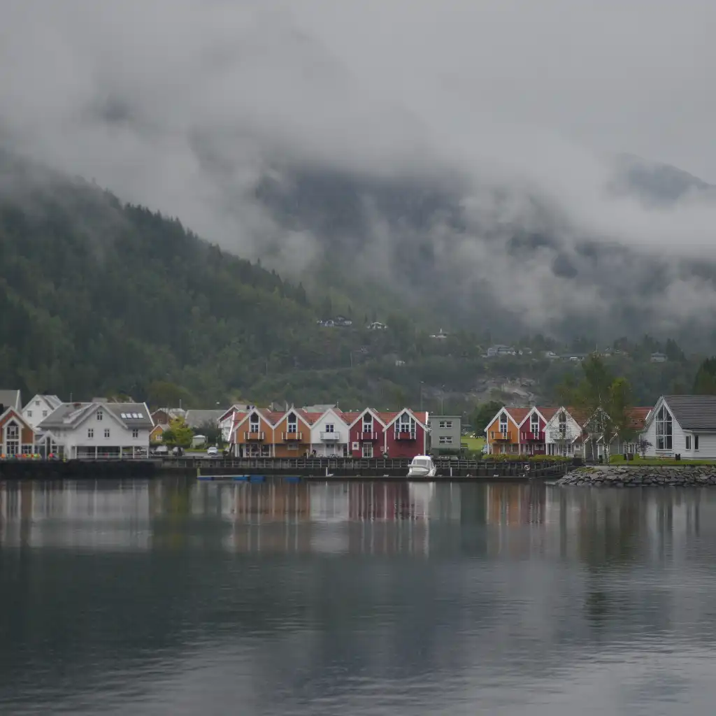 Mostraumen Norway colorful waterfront houses reflecting in calm fjord with misty mountains