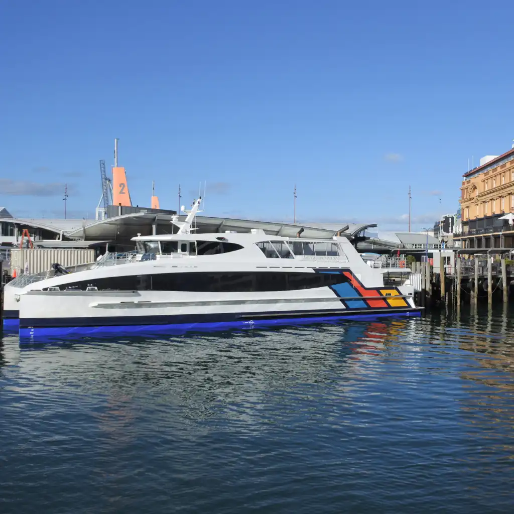 Auckland Ferry with colorful stripes docked at sunny waterfront pier in Auckland