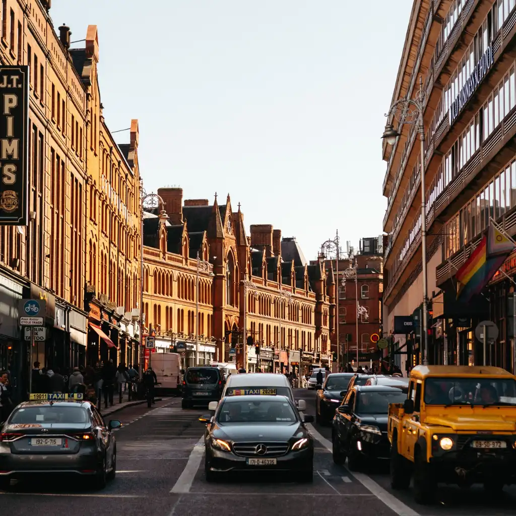 Dublin taxis cruising historic city streets lined with brick buildings and shops at dusk