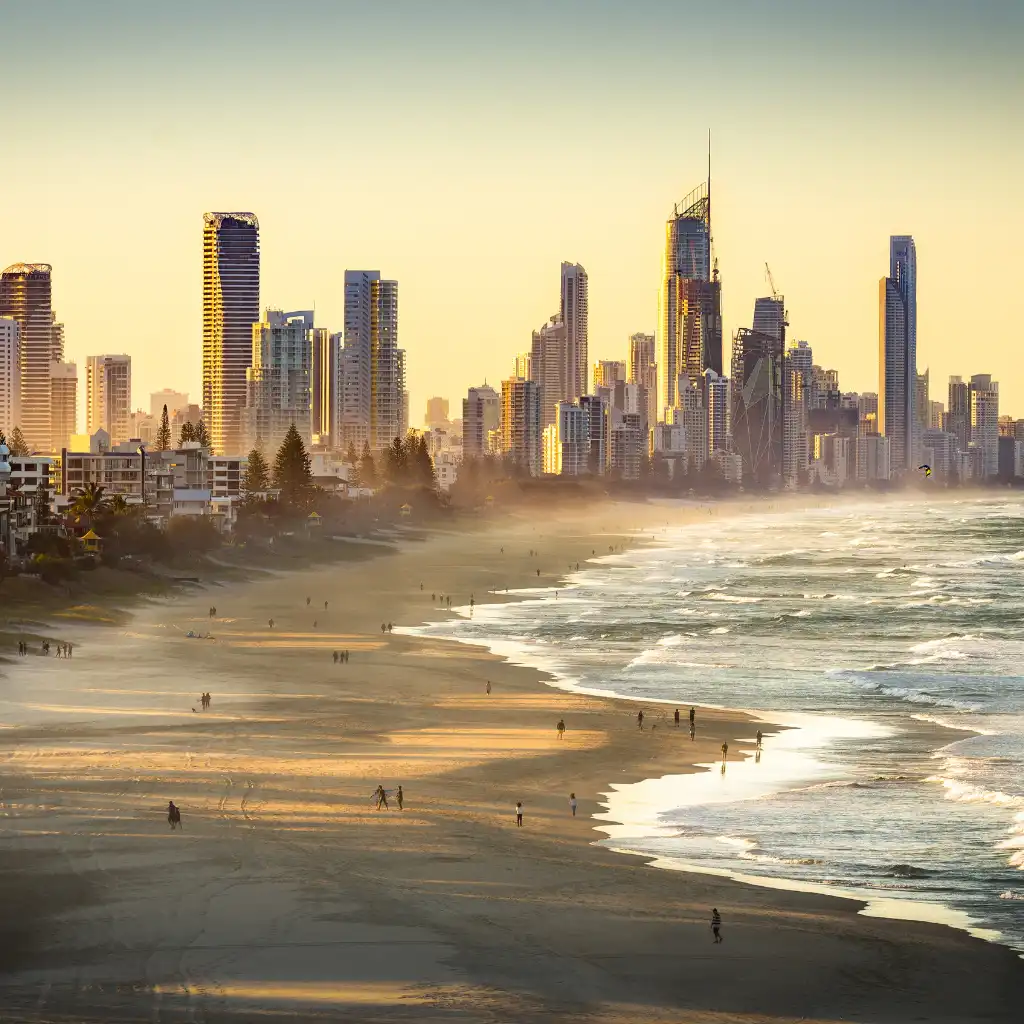 Gold Coast Skyline glowing at sunset over Surfers Paradise beach with ocean waves