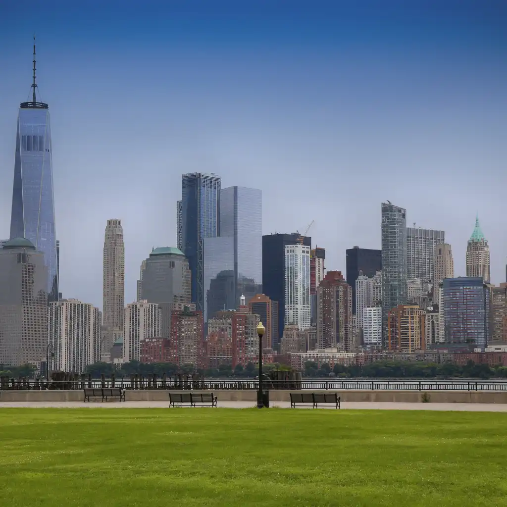Liberty State Park New York skyline view with One World Trade Center from waterfront lawn benches