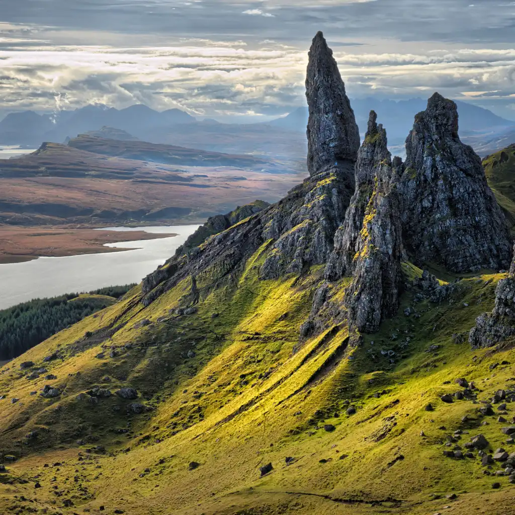 Old Man of Storr, Scotland towering rock formation on grassy hillside with loch and mountain views