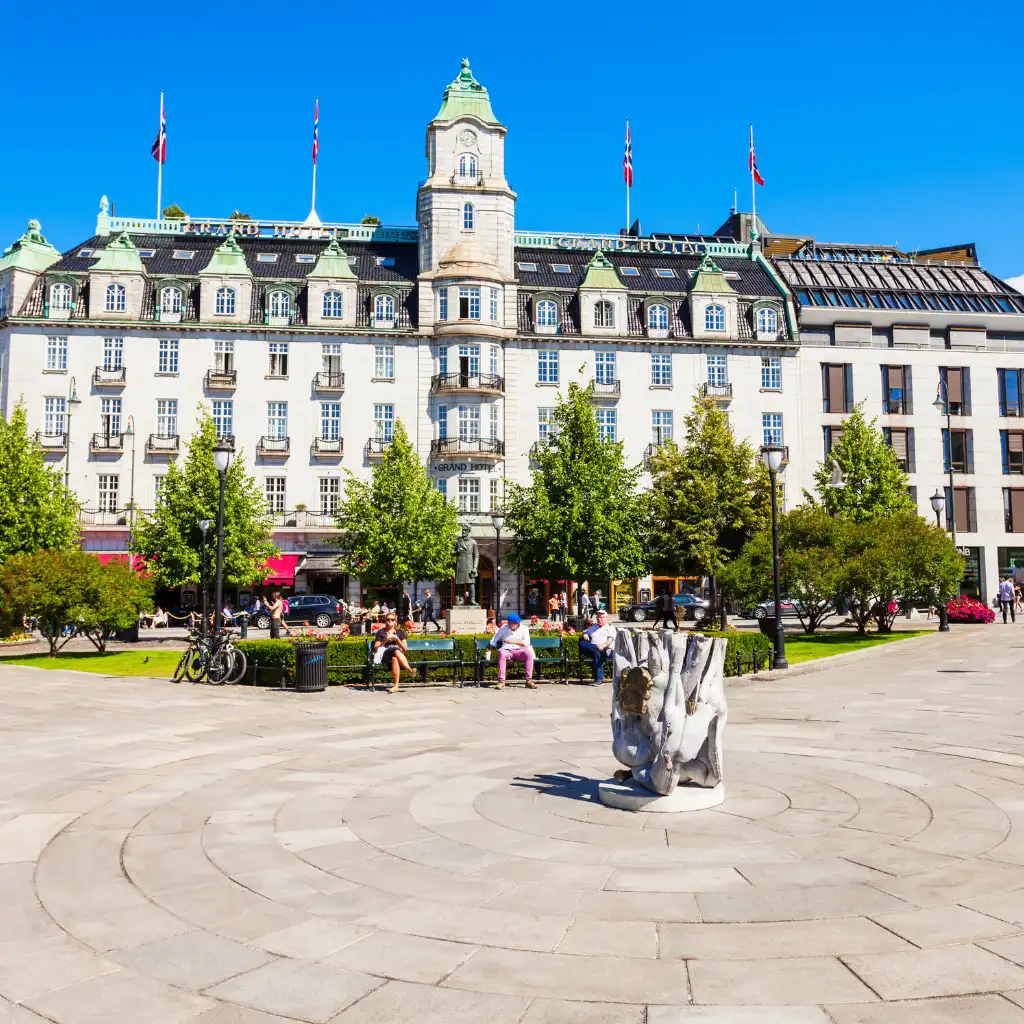 Oslo Grand Hotel Norway overlooking square with sculpture, trees and historic clock tower