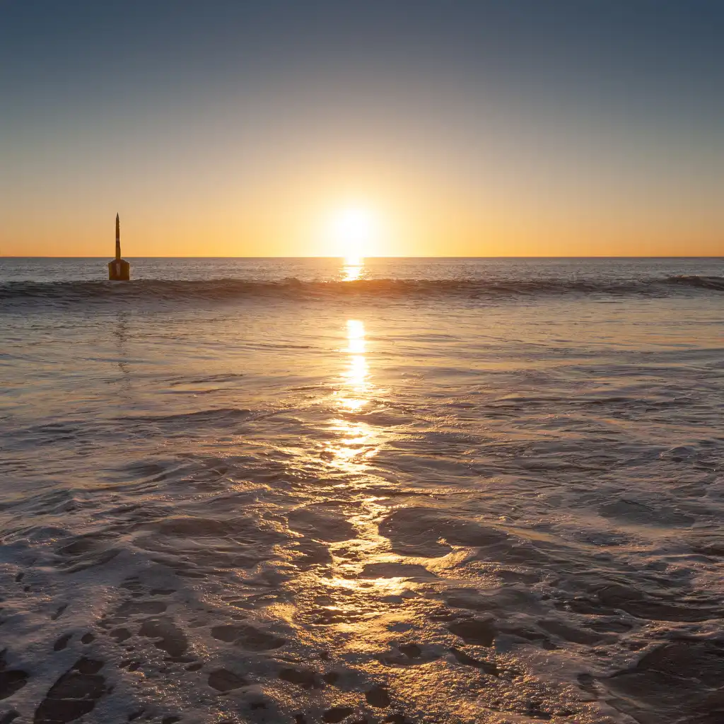 Cottesloe Beach sunset Perth with golden waves reflecting sunlight over the ocean at dusk