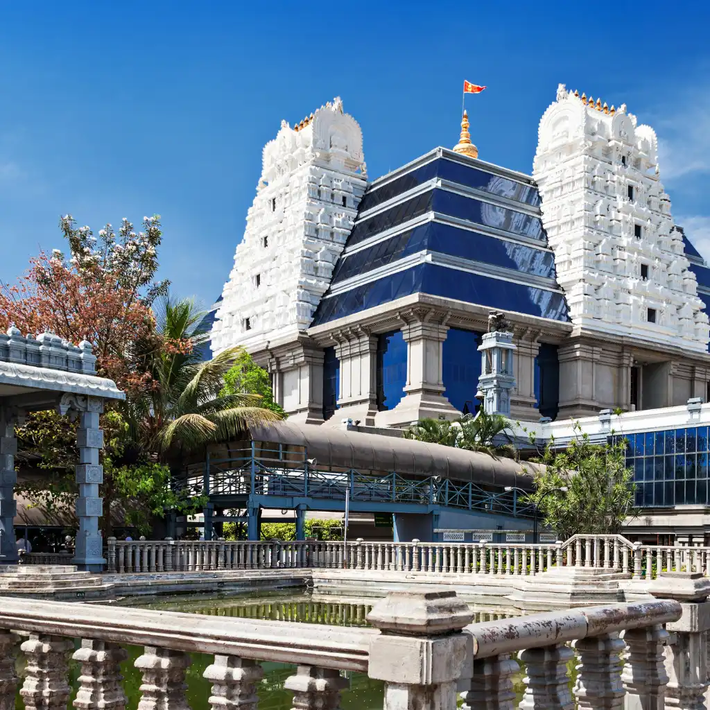 ISKCON Temple Bangalore with white gopurams, blue roof and serene foreground pond
