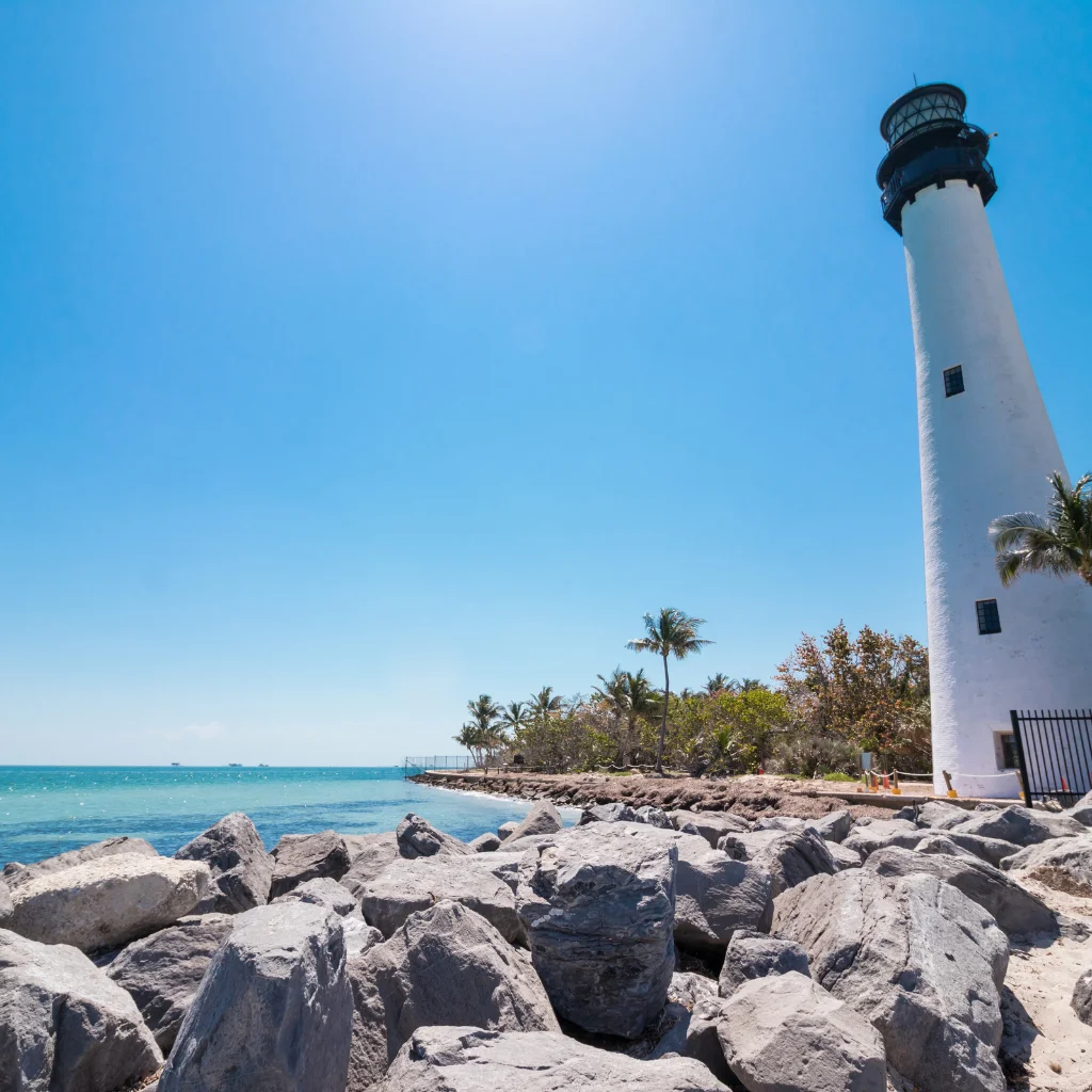 Key Biscayne Florida lighthouse on rocky shore with turquoise waters and palms