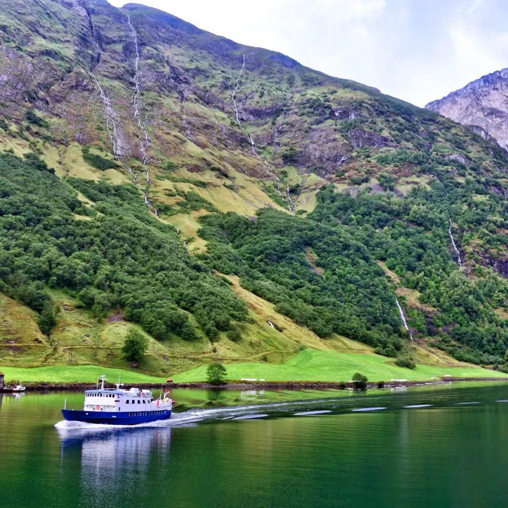 Naeroyfjord ferry cruise Norway with steep green cliffs and waterfalls closing in