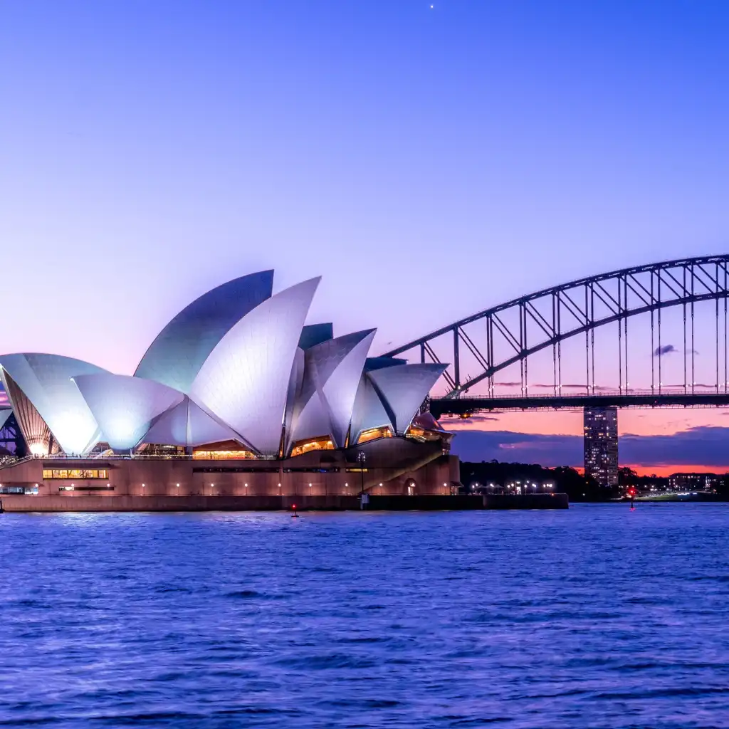 Opera House, Sydney glowing at dusk with Harbour Bridge over the water