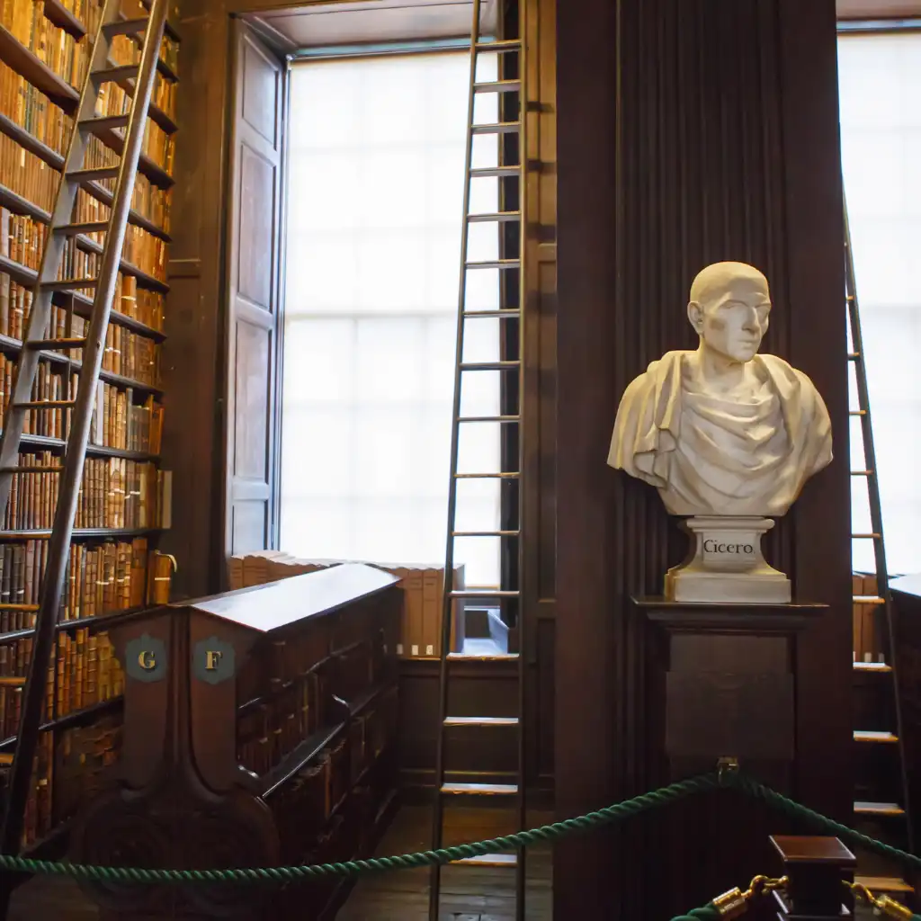 Trinity College Ireland library interior with towering bookshelves ladders and Cicero bust
