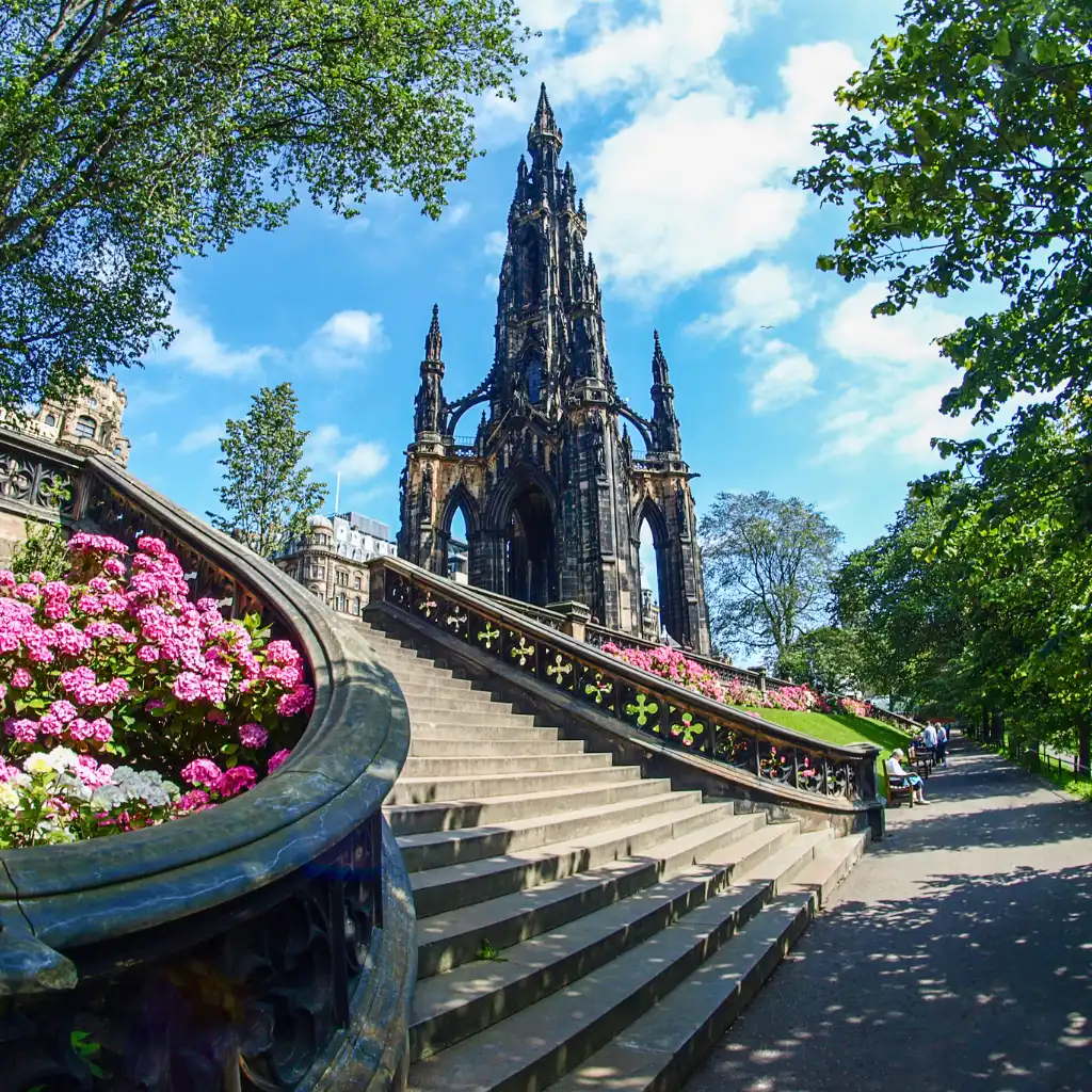 Scott Monument Edinburgh with pink flowers along grand stone staircase in sunlight