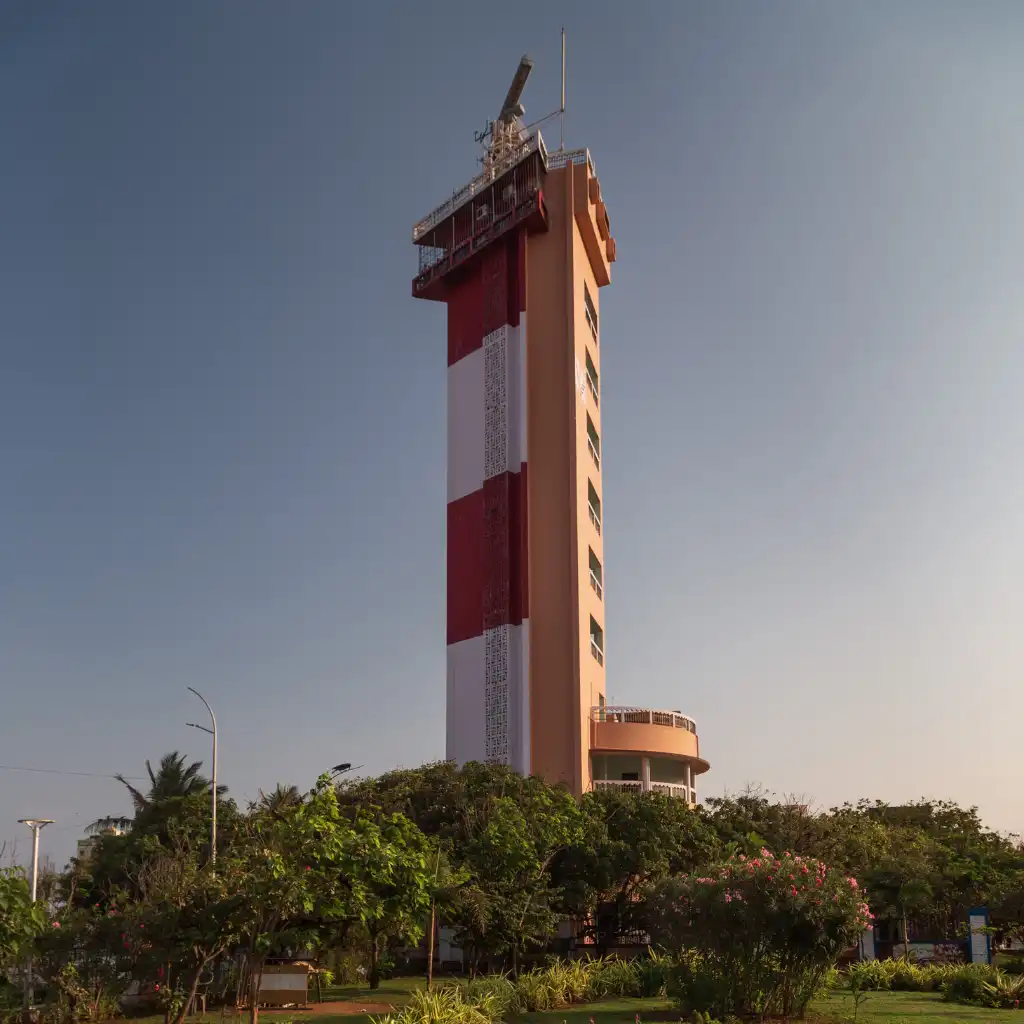 Chennai Lighthouse red and white striped tower rising above green trees in Chennai