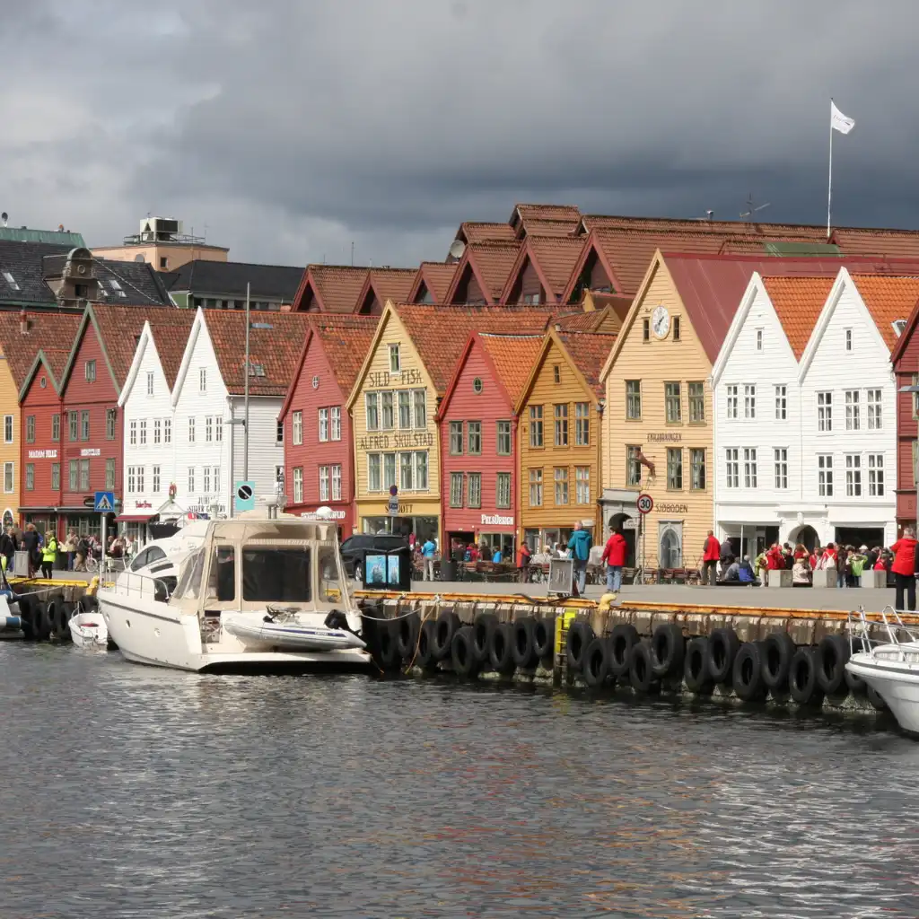 Bryggen Norway colorful wharf with historic gabled buildings, docked boats and visitors strolling the waterfront