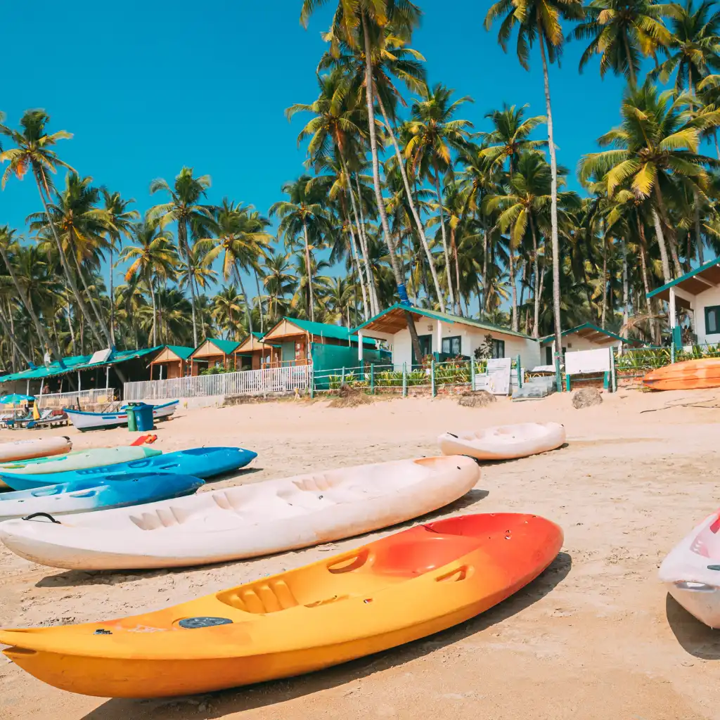 Colorful kayaks on Palolem Beach Goa sand with palm trees and beach huts