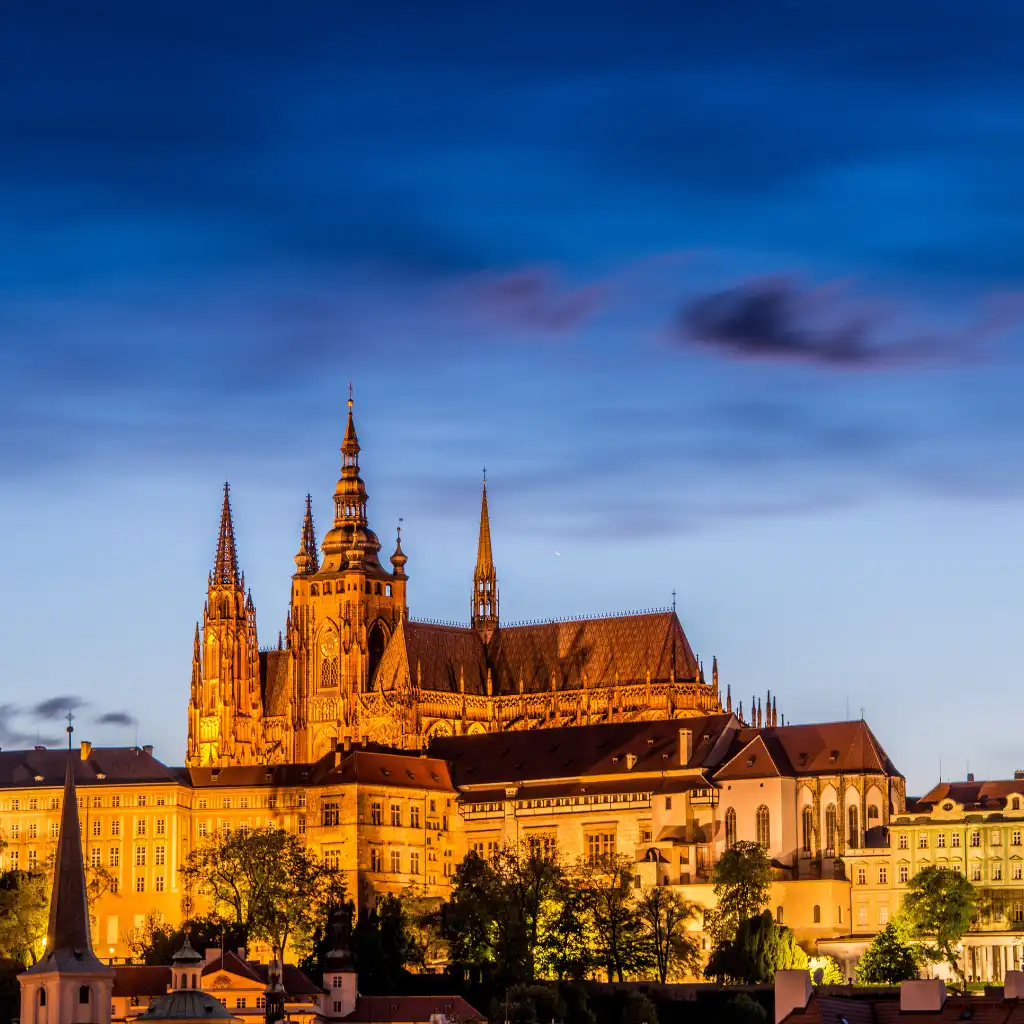Prague Castle illuminated at dusk with golden spires and towers in Prague
