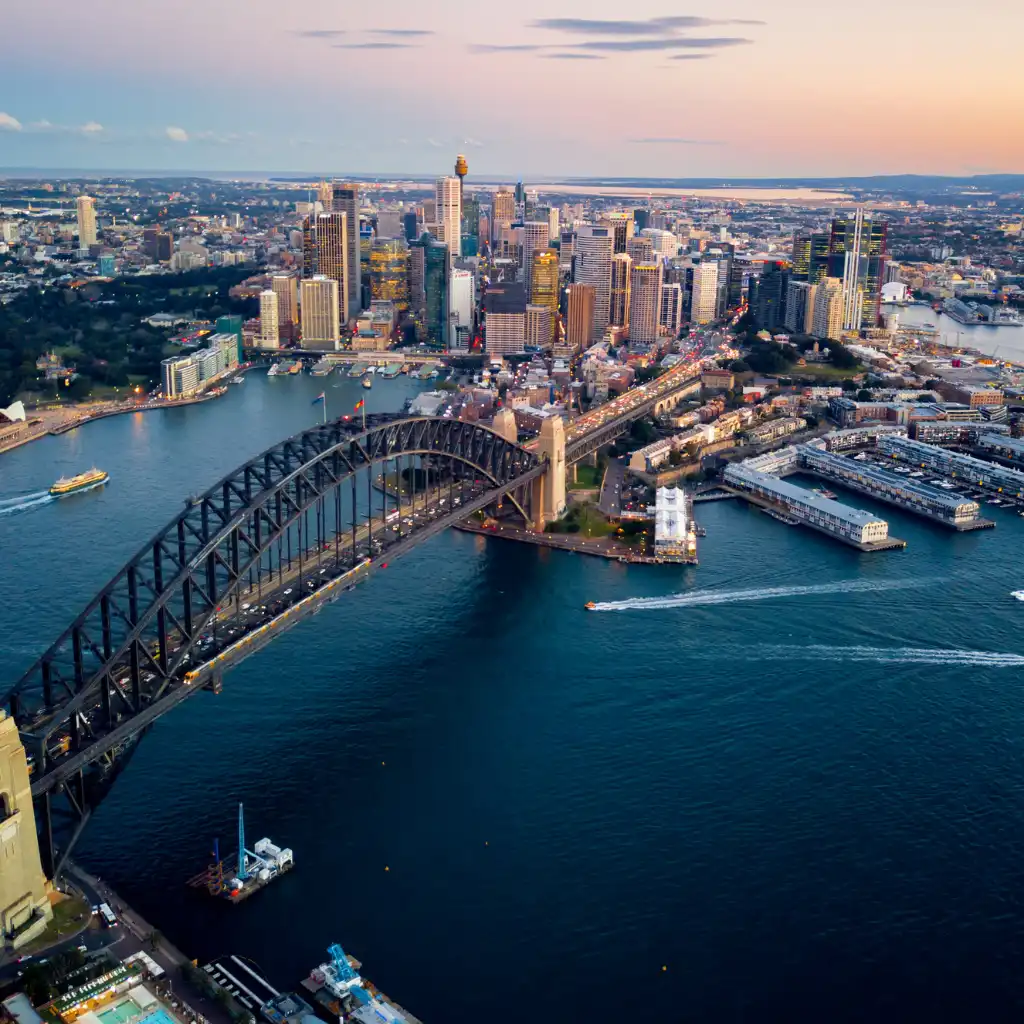 Sydney Harbour Bridge with Sydney skyline and boats on the water at dusk