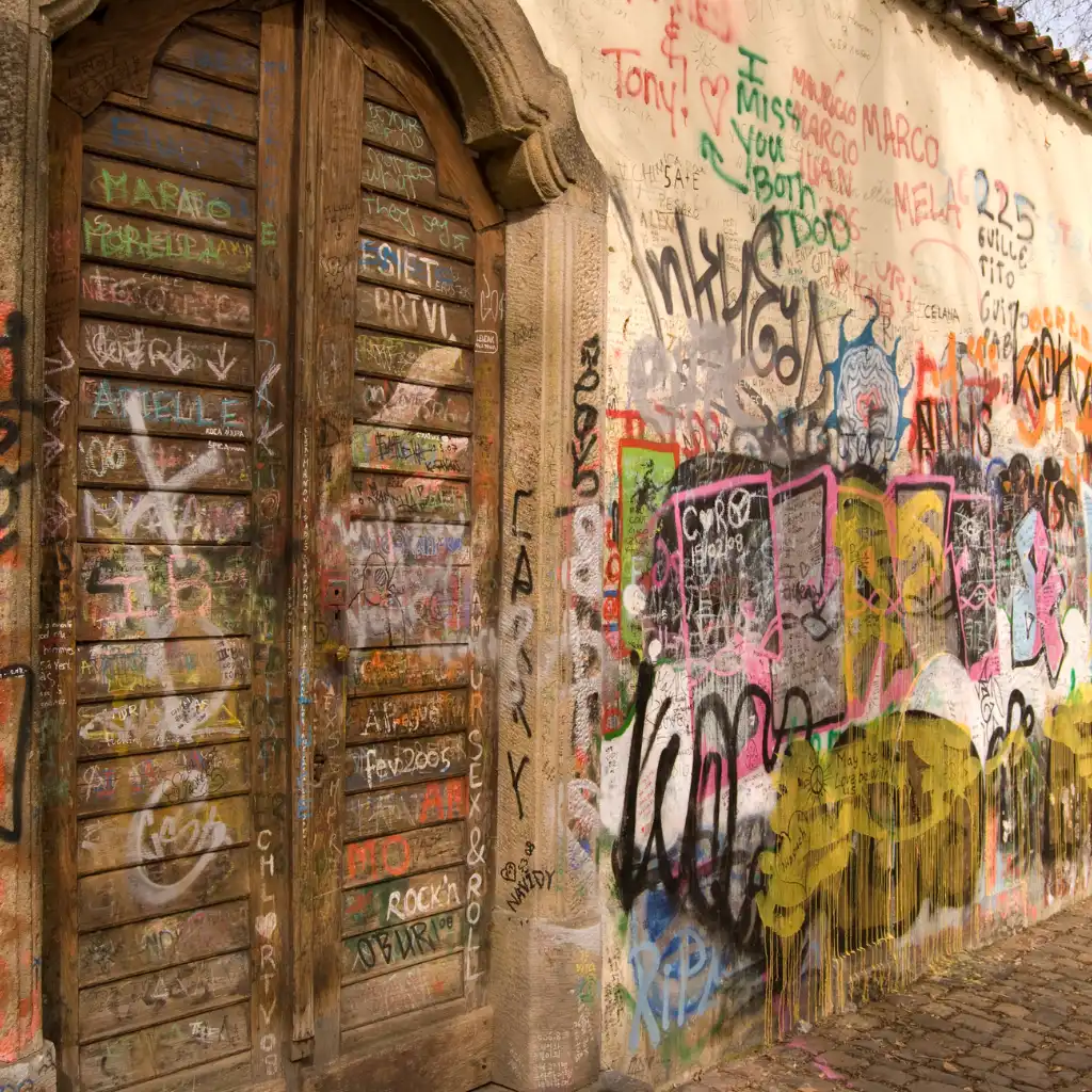 Lennon Wall Prague wooden door and wall covered in colorful graffiti messages and art