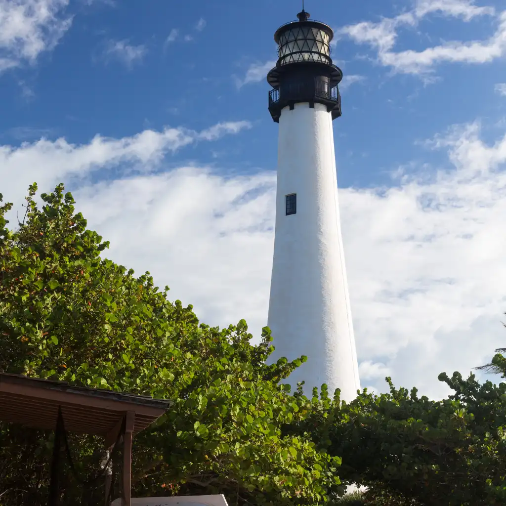 Bill Baggs Cape Florida lighthouse above picnic shelter and lush greenery under blue skies