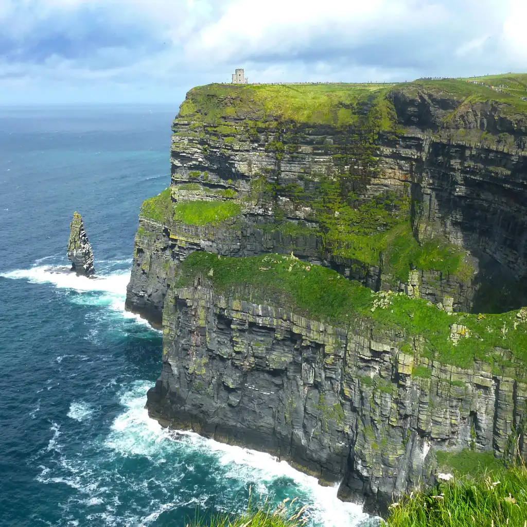 Cliffs of Moher Ireland with O'Brien's Tower, green clifftops and waves crashing on sea stacks along the Atlantic