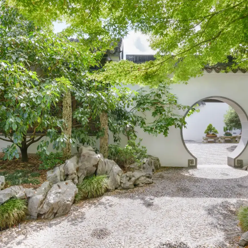 Lan Su Chinese Garden Portland moon gate amid rocks, trees and pebble path