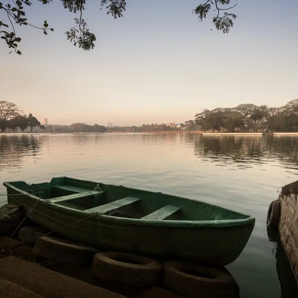 Green rowboat moored at Ulsoor Lake Bengaluru calm waters city skyline at dusk