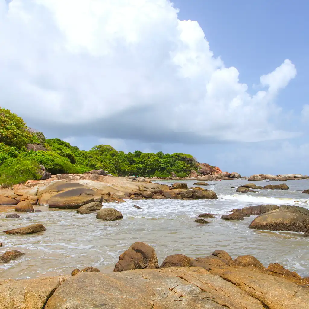 Agonda Beach Goa rocky shoreline with waves, boulders and green coastal hills