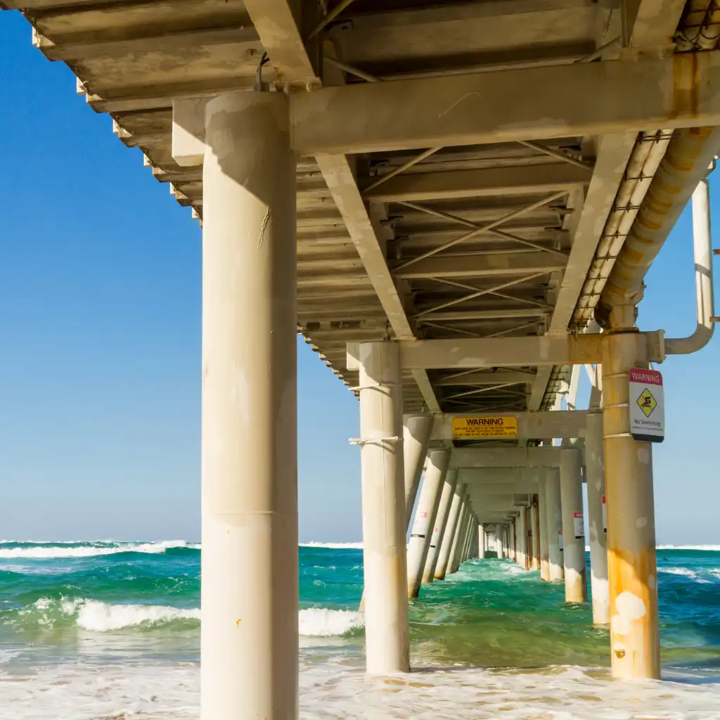 The Spit Gold Coast under pier with turquoise waves and warning signs