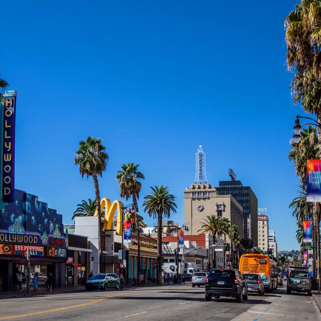 Beverly Hills, Los Angeles palm-lined street with traffic, McDonald's and iconic buildings under blue skies