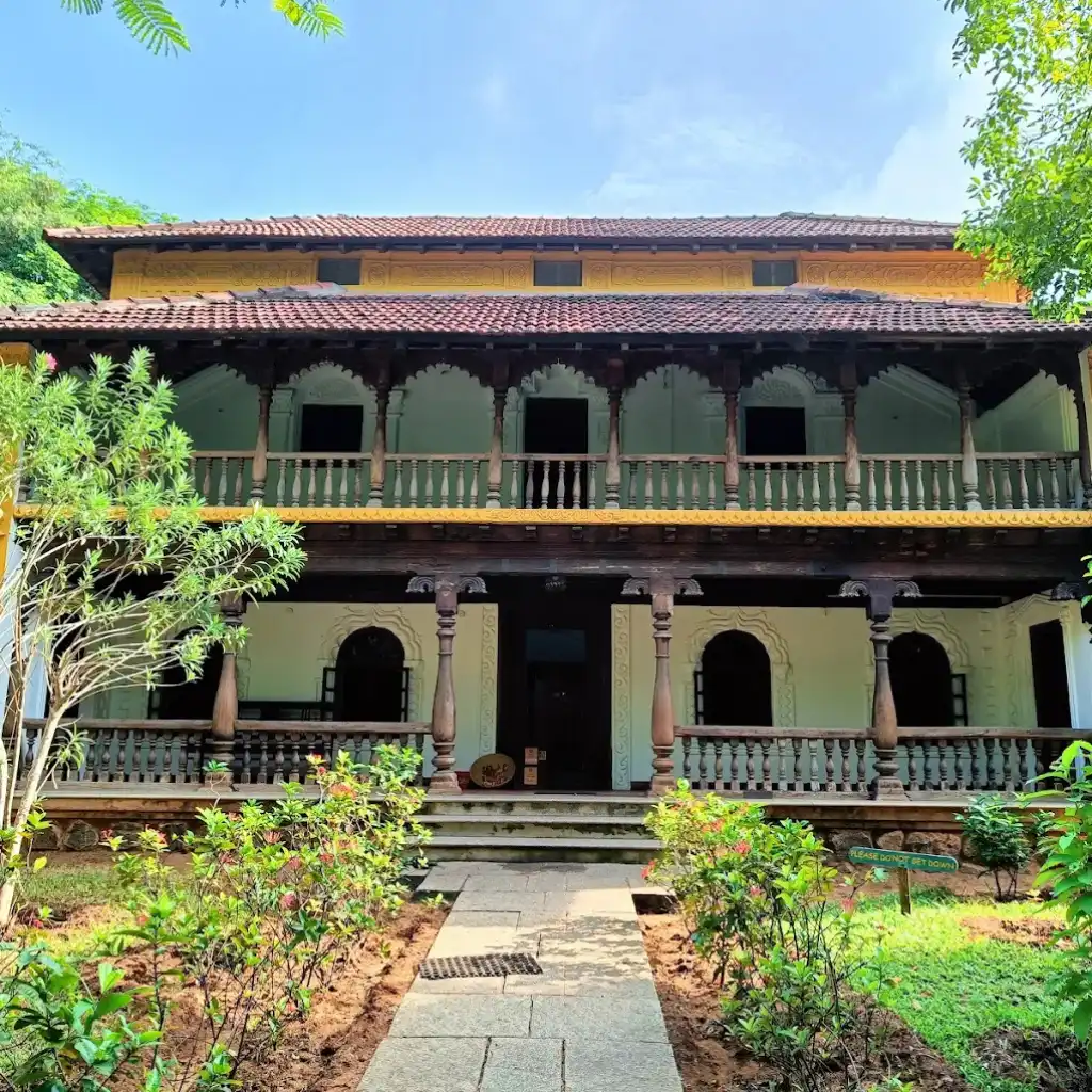 House at DakshinaChitra Chennai with arched balcony, wooden pillars and garden pathway