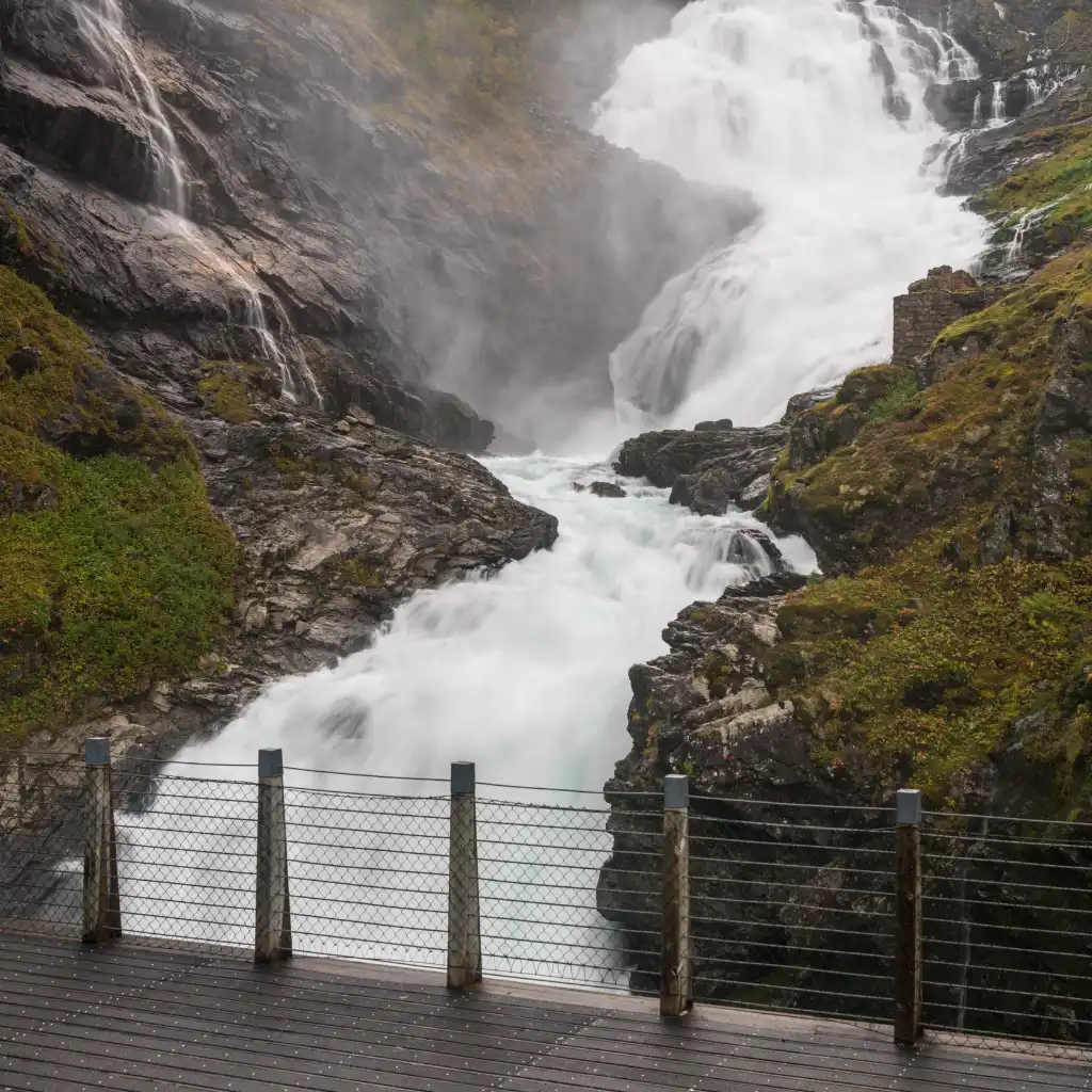 Kjosfossen Norway waterfall cascading over rocky cliffs viewed from wooden platform with fence