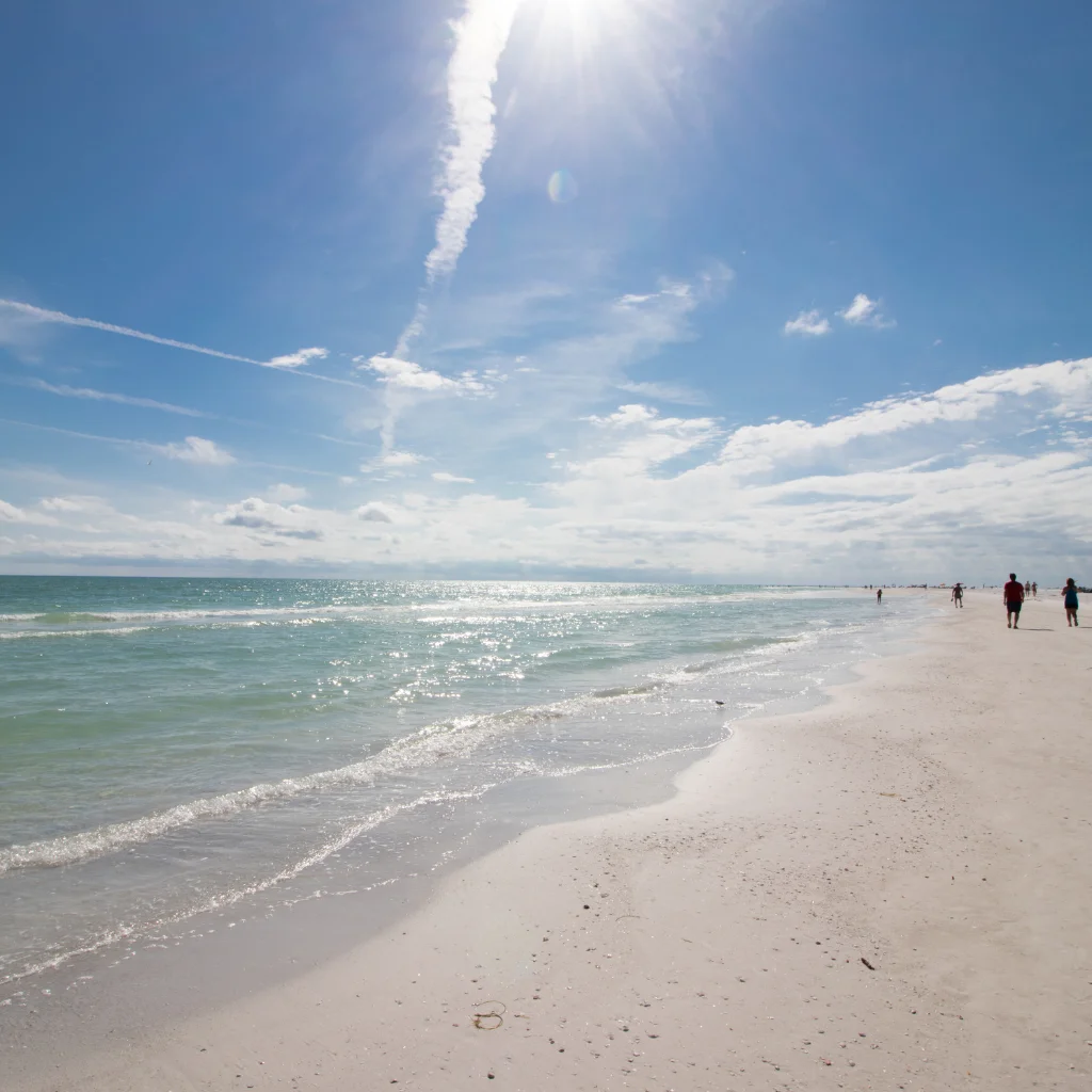 Siesta Beach Florida white sand shoreline with turquoise waves sparkling under bright sun and blue sky