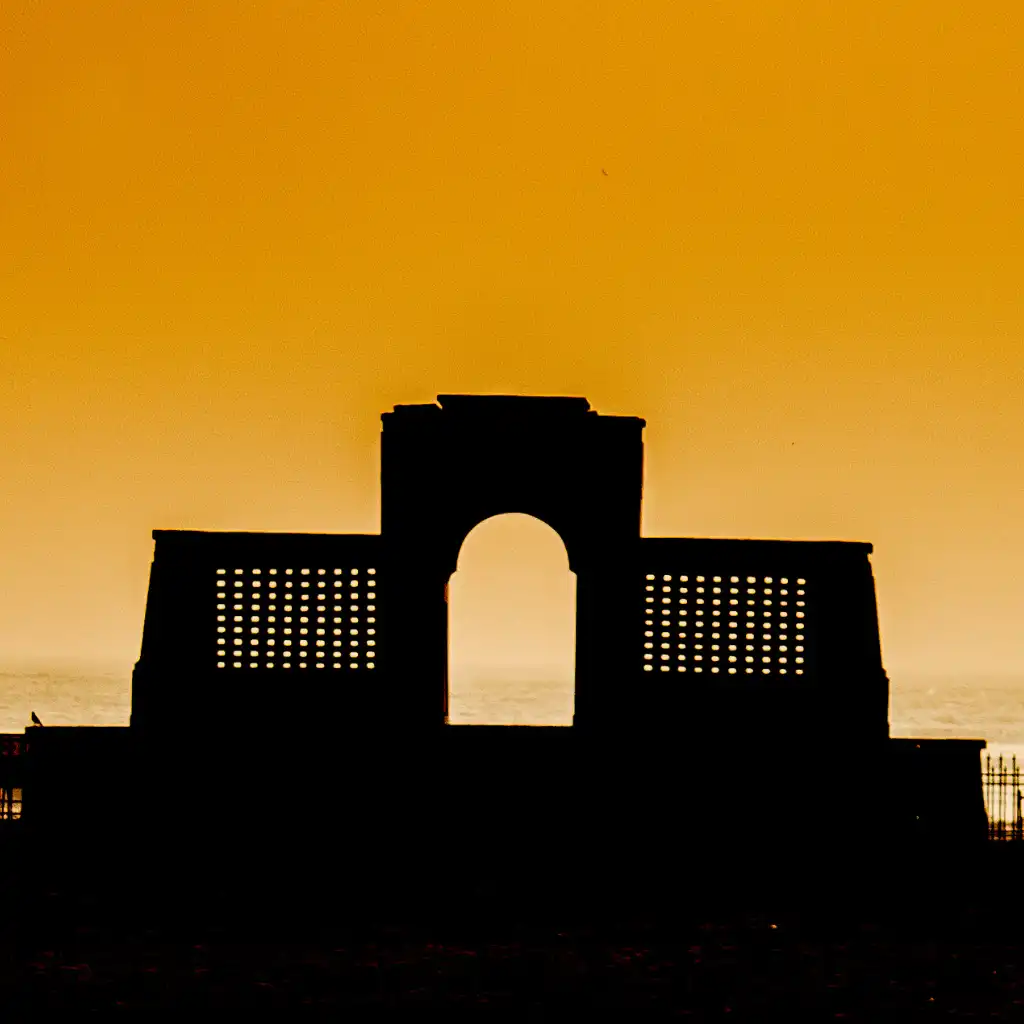 Chennai India arched monument silhouetted at vibrant sunset by the sea on Elliot's Beach