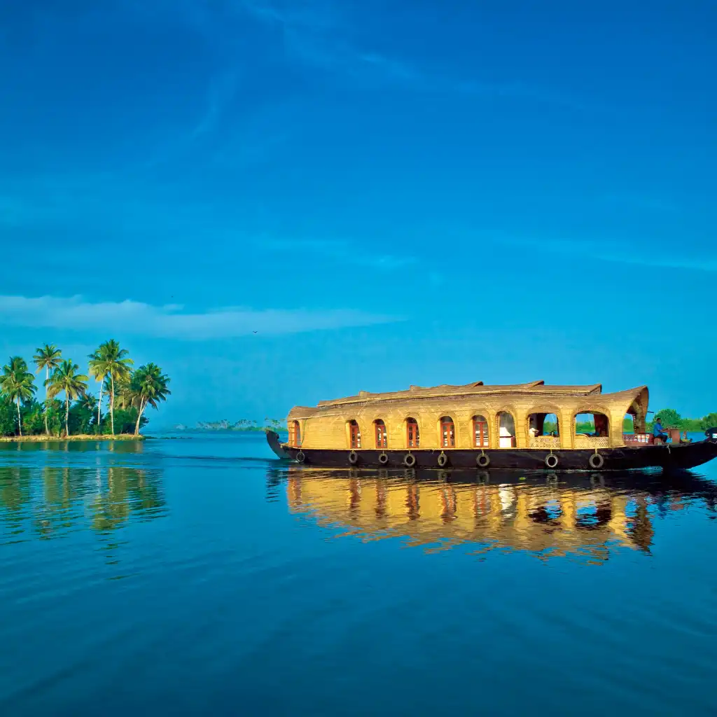 Kerala, India houseboat on serene backwaters with palm trees and blue sky reflection
