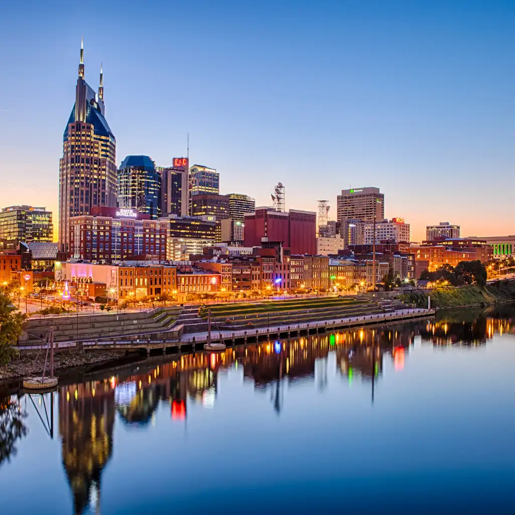 Nashville skyline at dusk with glowing skyscrapers reflecting in the Cumberland River