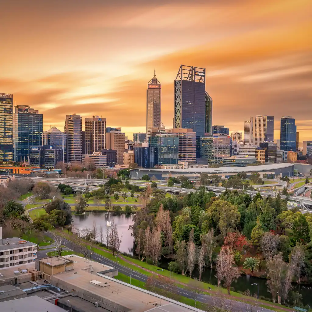 Perth's skyline at sunset with skyscrapers overlooking a lake and lush green park